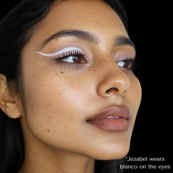 Model wearing a bold, white graphic winged eyeliner using Ashunta Sheriff UV Vegan Paint Liner in Blanco.