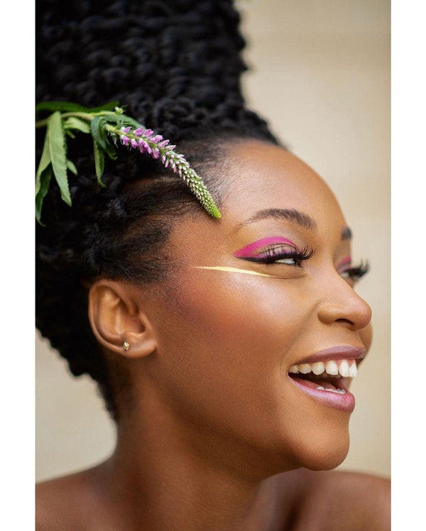 Model wearing vibrant pink and gold UV vegan paint liner in a bold, graphic winged eye makeup look.