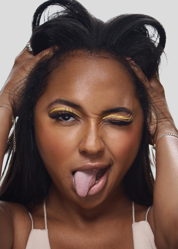 Model winking with vibrant yellow UV vegan paint liner on eyelids, showcasing a bold, smudge-proof makeup look.