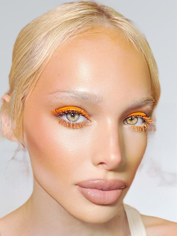 Model wearing vibrant orange UV vegan paint liner on eyelids with matching orange mascara for a bold, glowing look.