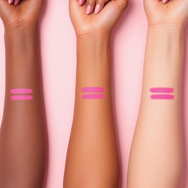 Three arms with different skin tones displaying vibrant pink UV vegan paint liner swatches on a soft pink background.