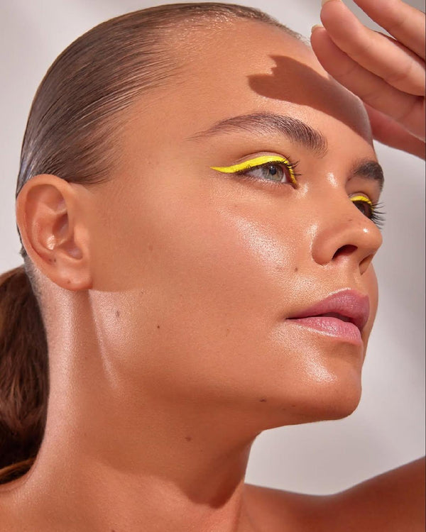 Model wearing vibrant yellow UV vegan paint liner in a sharp, precise winged cat-eye style.