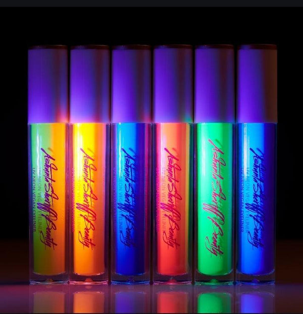 Six vibrant UV vegan paint liners in neon shades, glowing against a dark background in clear tubes with black caps.